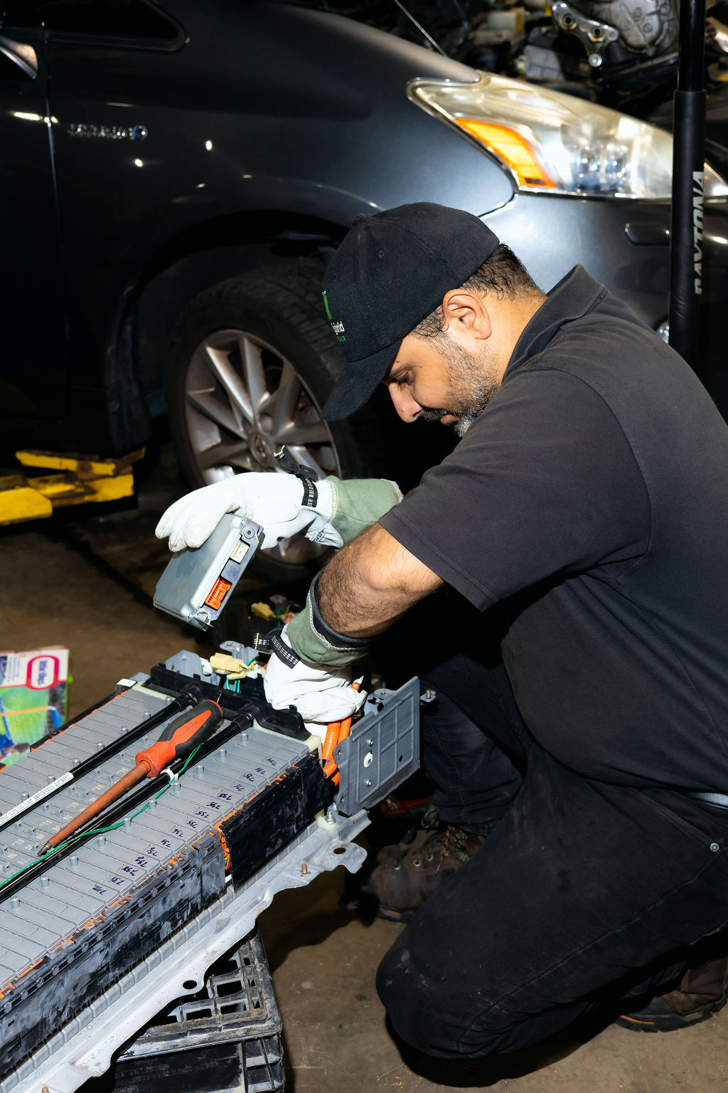 Sal installing a hybrid battery pack with insulated gloves at Triton Hybrid Battery Repair in Lorton, VA