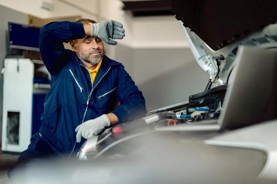Technician running engine diagnostics with a scan tool and laptop
